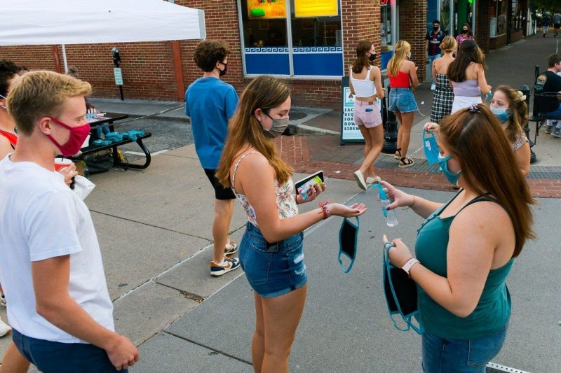 Students distribute hand sanitizer and pass out masks on College Avenue in downtown Blacksburg. Photo by Ryan Young for Virginia Tech