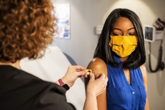 Photo of a woman placing a band aid on another woman
