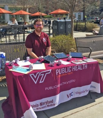 MPH student Steven Black sits at his informational table outdoors on campus