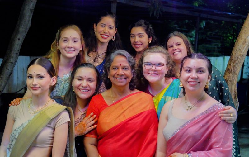 A group of students dressed in colorful saris gathered around the director of Aarti for Girls 